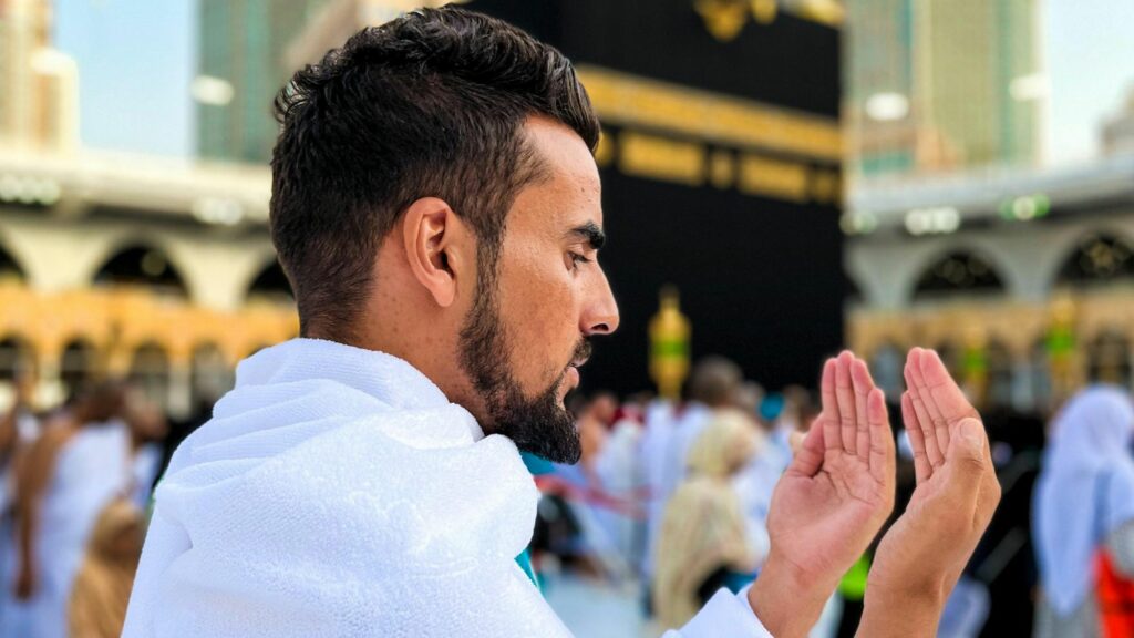 A boy praying in front of the Holy Kaaba utilising comprehensive Umrah packages for a spiritual journey