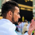 A boy praying in front of the Holy Kaaba utilising comprehensive Umrah packages for a spiritual journey