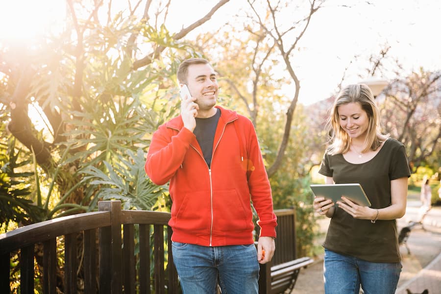 A couple walks down a path, discussing on their cell phones, discovering internet deals and comparisons through TalkWalk Connection