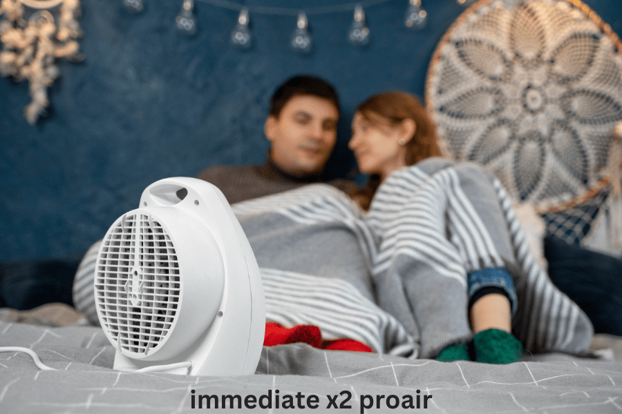 A couple relaxes in bed, enjoying warmth from a heater, with the Immediate X2 ProAir air purifier nearby.