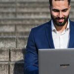 An Amazon virtual assistant sitting on stairs while using his laptop