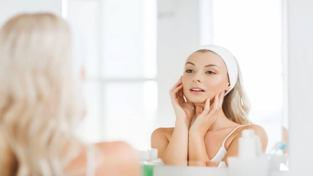 A beautiful woman gazes at her reflection in the mirror, showcasing her confidence and self-care routine with cellulogia.