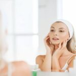 A beautiful woman gazes at her reflection in the mirror, showcasing her confidence and self-care routine with cellulogia.