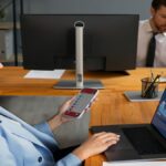 A woman uses a remote control to operate a computer, demonstrating remote access technology.cbybxrf